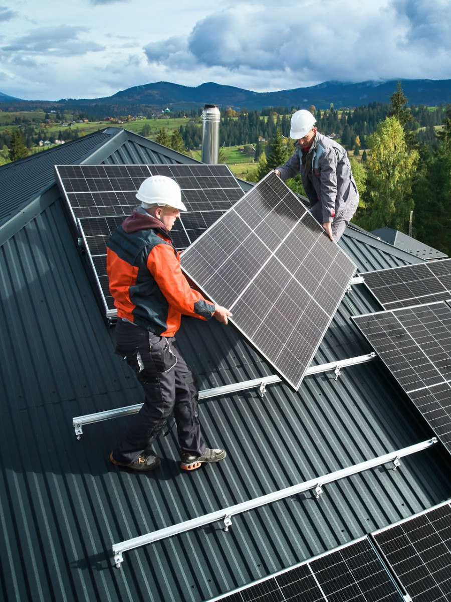 Zwei Arbeiter bringen Solar-Panels  auf einem Dach an.