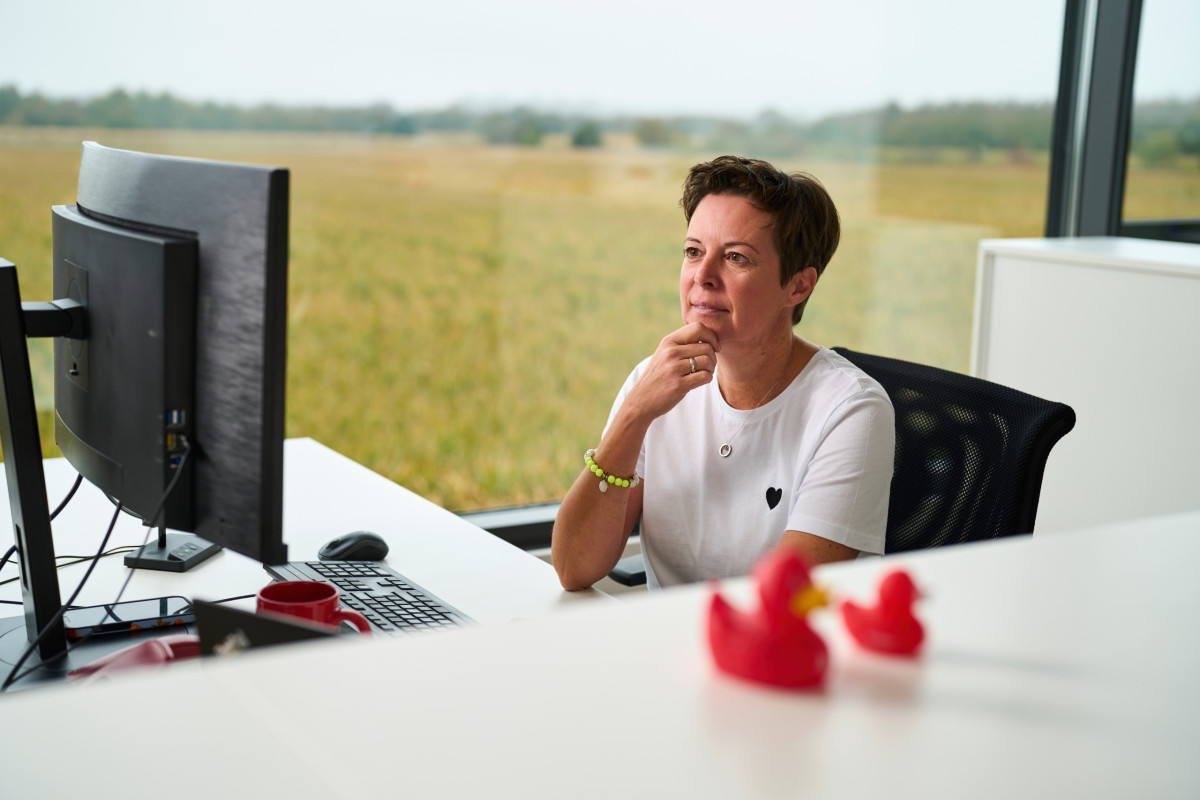 Mitarbeiterin Sandra sitzt am Schreibtisch bei Fritz, im Vordergrund 2 rote Enten