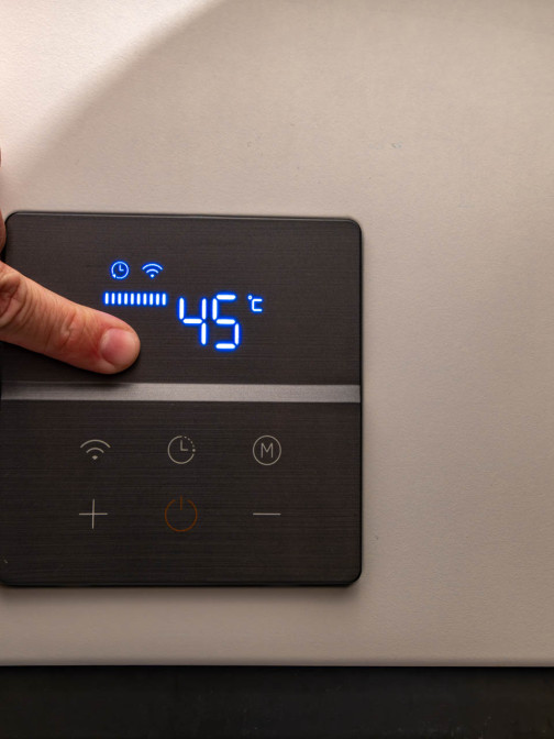 Person tippt auf ein schwarzes Tablet, um die Temperatur zu regulieren